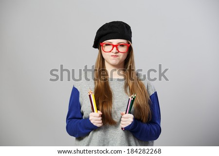 Funny girl at beret holds pencils at both hands