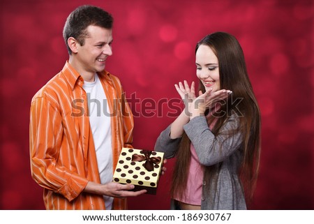 Boy gives present to girl at light background