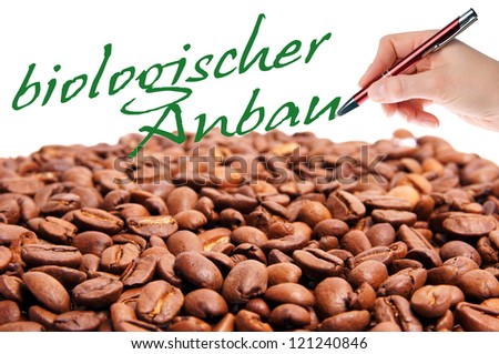 coffee beans and hand with pen writes the german words organic farming / organic farming