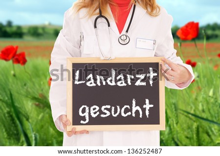 Doctor with sign and the german words Looking for a country doctor / Looking for a country doctor