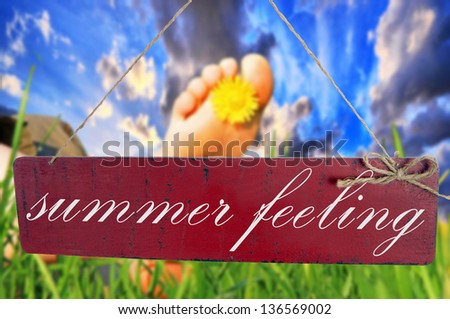 Foot in green grass with sign and the words summer feeling / summer time