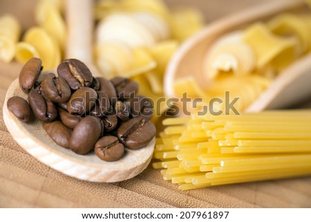 Wooden spoon with pasta and coffee beans on a wooden board / Pasta