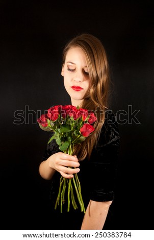 A young beautiful woman with a bouquet of roses on a black background
