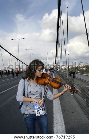 ISTANBUL,TURKEY - OCTOBER 28: Unidentified girl plays violin on the Bosphorus Bridge during the 27th Intercontinental Eurasia Marathon on October 28, 2007, in Istanbul, Turkey