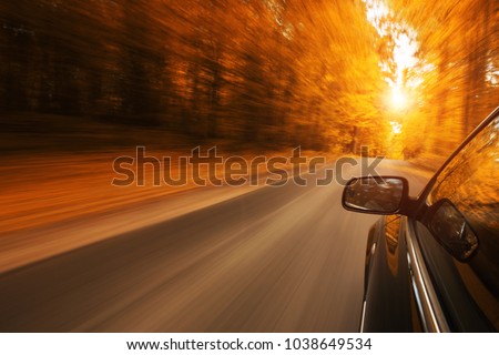 Close up of a car speeding on the empty, autum road with copy space
