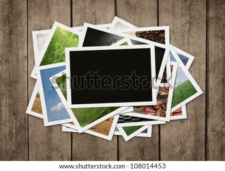 Stack of old photographs at grunge wooden background with clipping path for the blank one