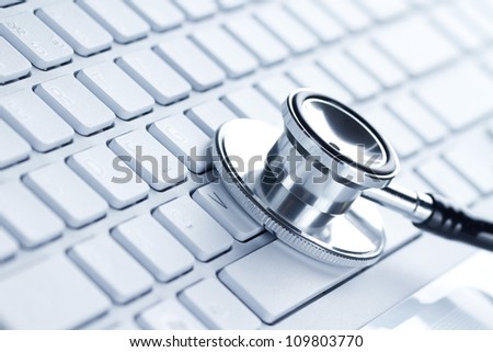Silver stethoscope lying down on an laptop, toned blue