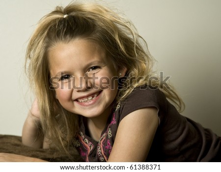 Smiling young girl wearing a brown shirt, looking at the viewer.