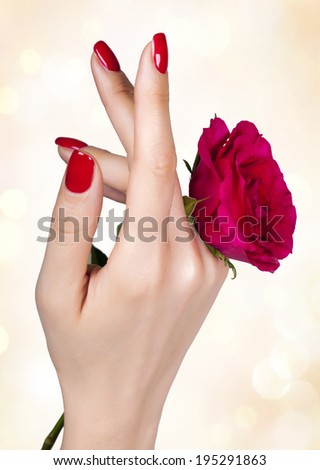 Red manicure on a woman\'s hand with red roses.