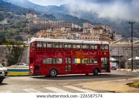 Gibraltar,  British Overseas Territory - JULY 11, 2013: Red bus on the street at the foot of Gibraltar rock. Entrance to Casemates Square.