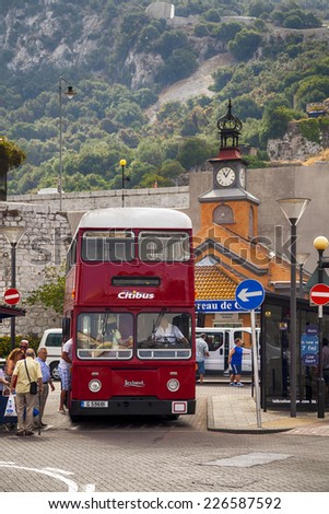 Gibraltar,  British Overseas Territory - JULY 11, 2013: Red bus on the street at the foot of Gibraltar rock. Entrance to Casemates Square