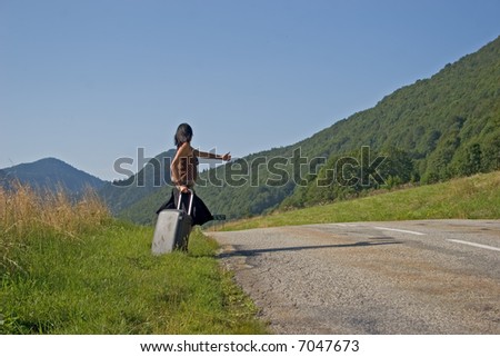 Woman on a mountain road making of hitch-hiking