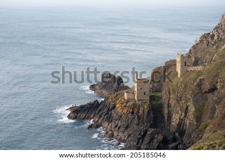 View of the two ruined engine houses of the Crown Mines , Botallack, Cornwall perched on a cliff overlooking the undersea shaft extending under the ocean floor in search of tin, now a heritage site