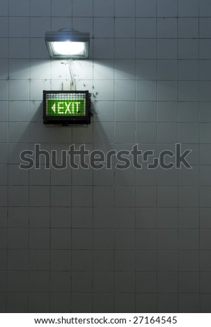 A grungy subway exit sign on a tiled wall