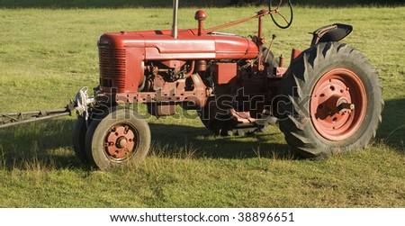 an old red tractor pictured in a field