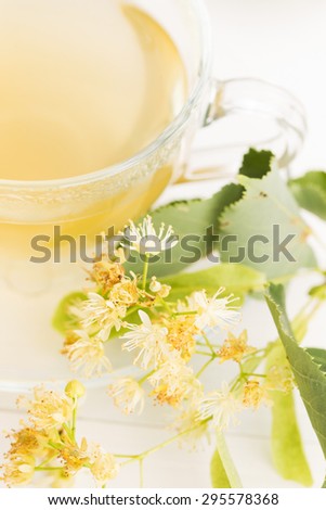 teapot and cup with linden tea and flowers