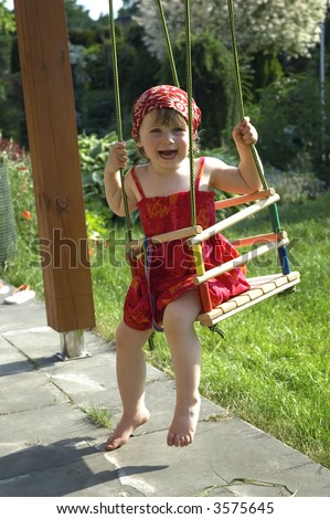 two-year-old girl on a swing in the garden
