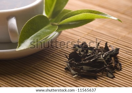 a cup of green tea with freh leaves on the bamboo tray