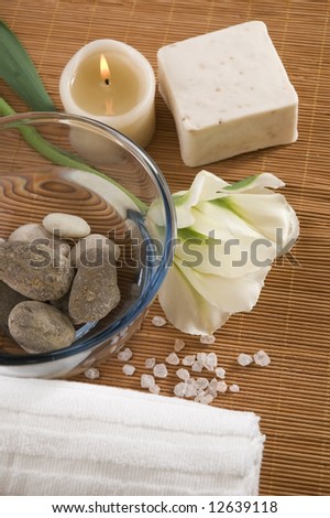 spa. welness products - bar of soap, towel, water, stones, candles and flower