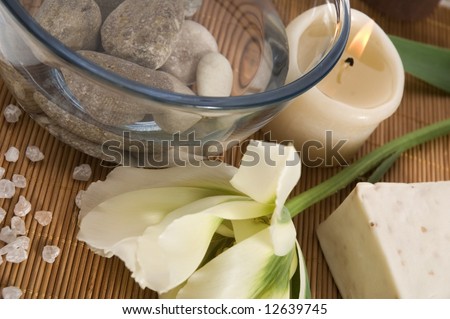 spa. welness products - bar of soap, towel, water, stones, candles and flower