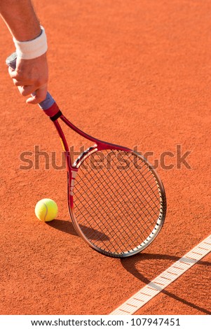 tennis ball and racket on the red clay court