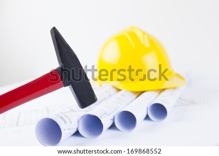 red hammer and yellow hard hat with construction blueprints