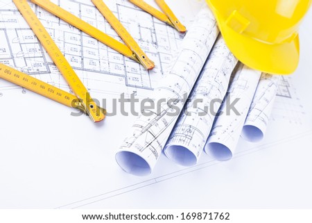 yellow hard hat and metric folding ruler with architectural drawings