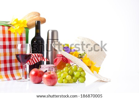 picnic basket with bottle of wine,fruits, bread and summer hat isolated on white
