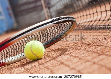 tennis ball and tennis racket on clay court