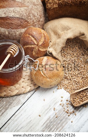 Freshly baked bread rolls, wheat ears and honey . Healthy breakfast concept