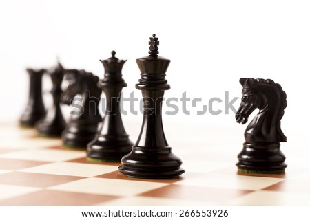 Black chess pieces on a chessboard standing in perspective