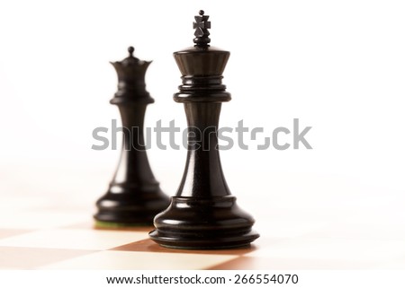 Black chess king and queen on a chessboard standing in perspective