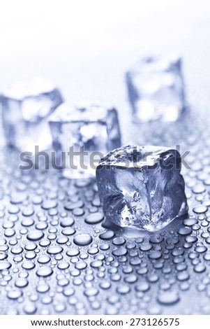 ice cube in focus, water drops background