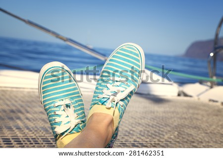 woman lounging on a catamaran sailboat trampoline with her feet propped up and crossed.