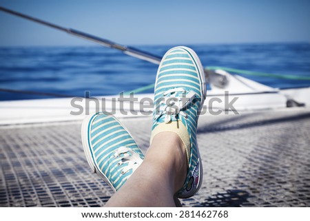 woman relaxing on a catamaran sailboat trampoline with her feet crossed