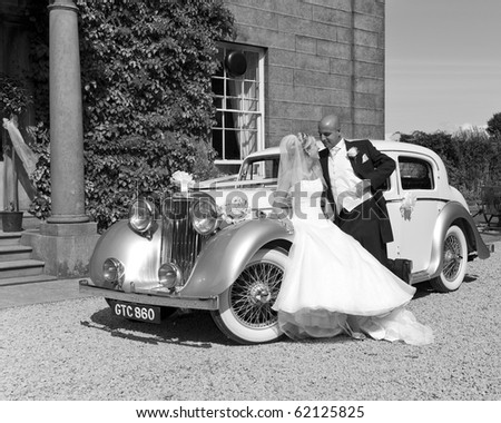 A stunning looking bride and groom next to a vintage wedding car