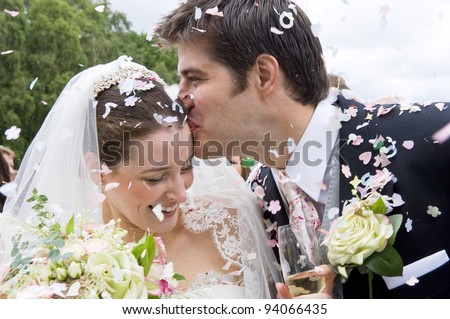 A really happy looking bride and groom being showered with confetti by their guests