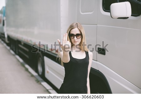 young woman with sunglasses near white cargo truck showing index and middle fingers