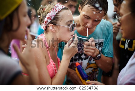 SAMARA,RUSSIA- JULY 24: young people throwing water at each other during Water Wars flash-mob , wet girls and young man taking a break and smoking a cigarettes , July 24, 2011, Samara, Russia