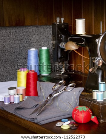 Retro sewing machine with sewing paraphernalia including thread, fabric, sewing needles, pin cushion, buttons scissors and thimble