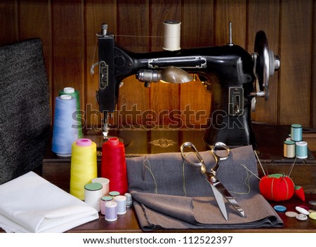 Retro sewing machine with sewing paraphernalia including thread, fabric, sewing needles, pin cushion, buttons scissors and thimble
