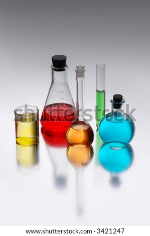 Chemical flasks with brightly colored liquids shot on a reflective surface