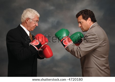 Two businessmen in business suites facing off with boxing gloves