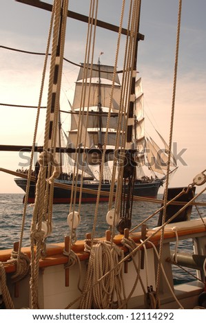 Vintage windjammer seen through the rigging of another vintage wooden ship