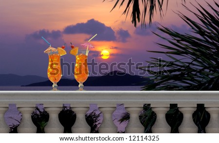 Two tropical fruit drinks with straws and umbrellas on a balcony with a tropical sunset in the background