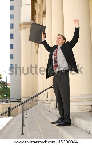 Attorney standing on the courthouse steps with both arms raised in a gesture of victory