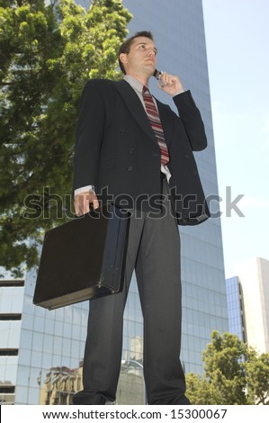 Worm\'s eye view of a businessman talking on cell phone with briefcase downtown