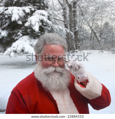 Santa looking over the top of his glasses against a snowy background