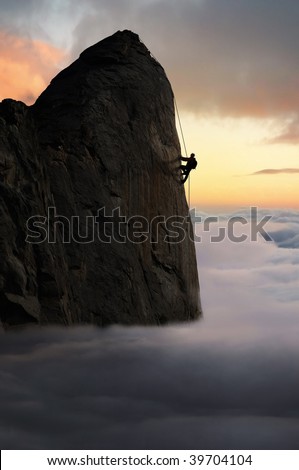 Profile of a mountain climber reaching the peak of a sheer rock face above the cloud base