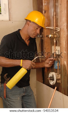 Plumber sweating a copper pipe with a propane torch